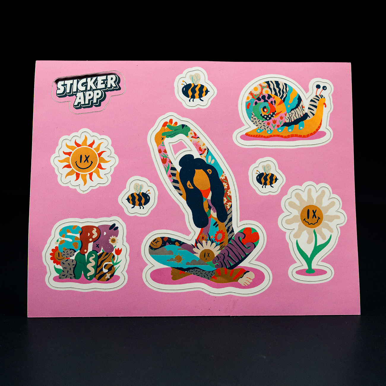 Colorful sticker sheet on a pink background featuring playful, nature-inspired illustrations. Includes a large illustrated leg with floral patterns, a snail, bees, flowers, and abstract organic shapes, along with a small “StickerApp” logo.