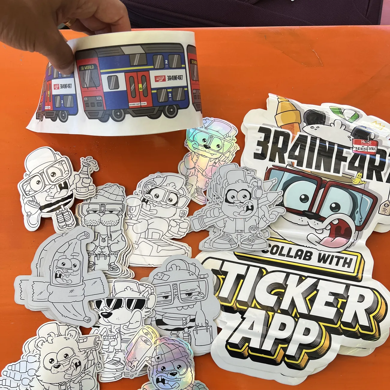 Brainfart x StickerAppin S8 World -junaetiketti, jossa on kyltti "In every fart is art", mustavalkoisten muotoon leikattujen tarrojen yllä