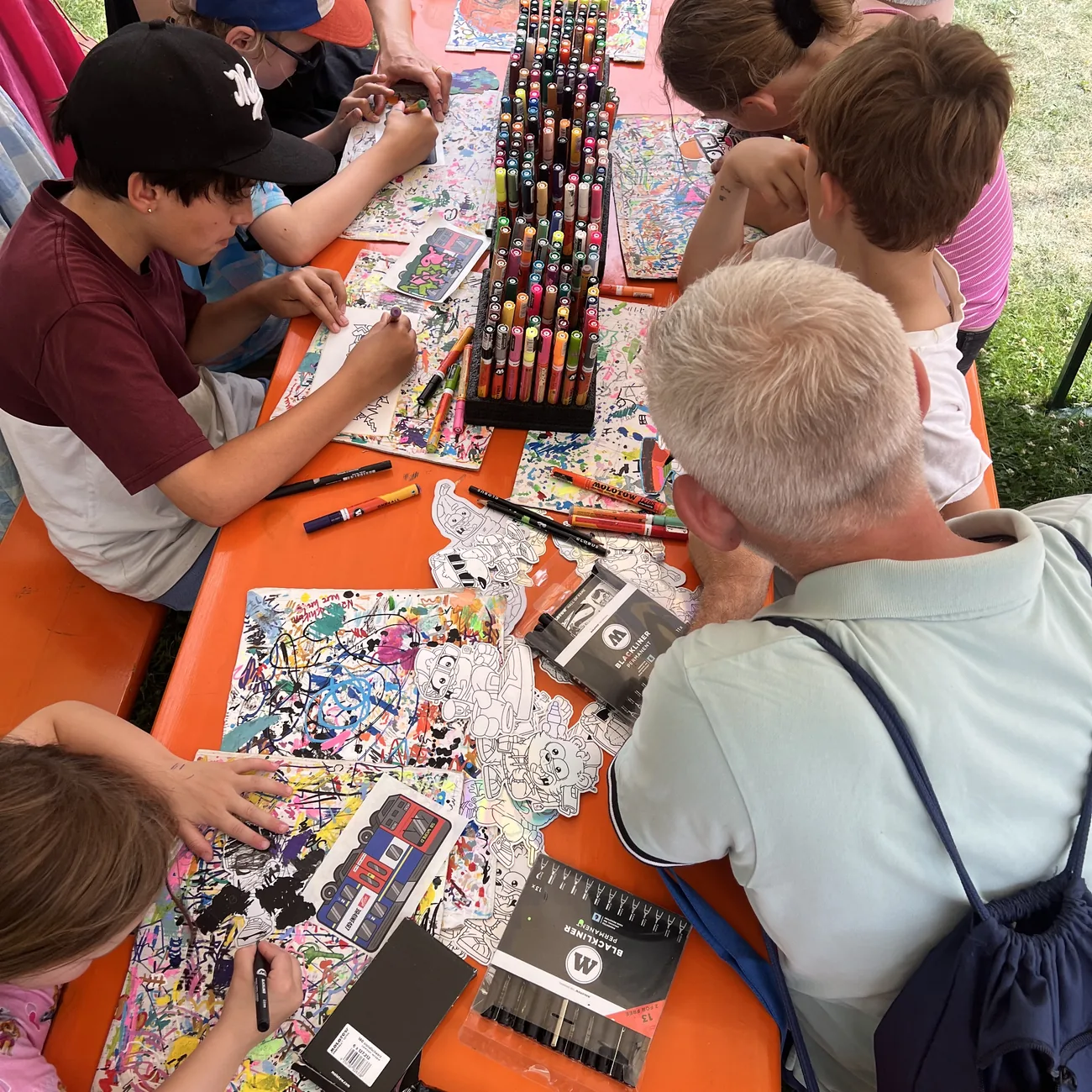 Lapset värittävät Brainfartin muotoon leikattuja tarroja maalitussitelineen ympärillä festivaalin ulkotyöpajassa