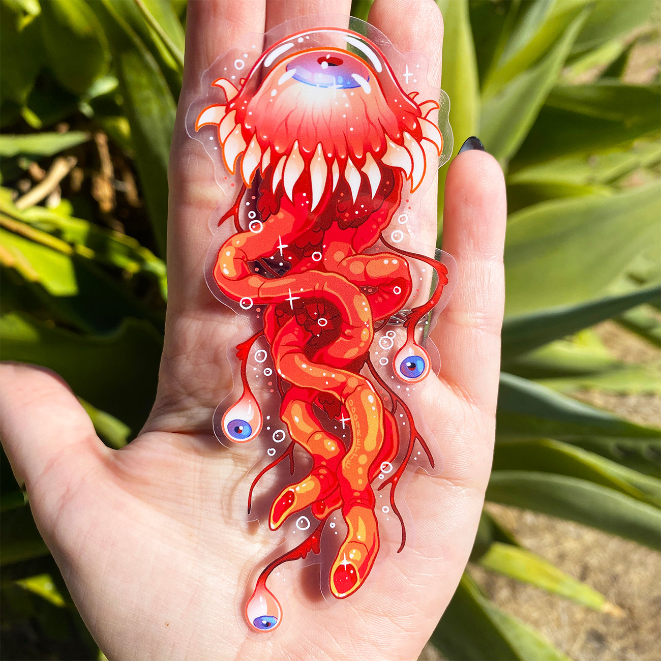 Oddarette holding a jellyflesh sticker; a red and orange creature with multiple eyes and tentacle-like appendages.