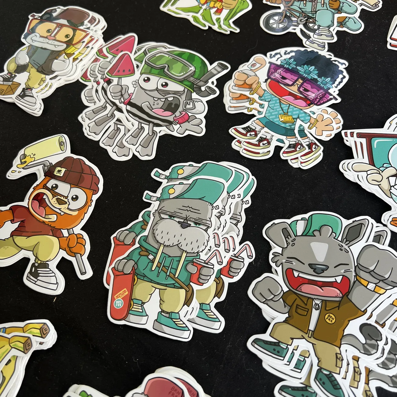 Brainfart x StickerAppin muotoon leikatut tarrat, joissa on katuvaatteisiin pukeutuneita sarjakuvahahmoja, kuten mursu rullalaudan kanssa ja virnistävä kissa