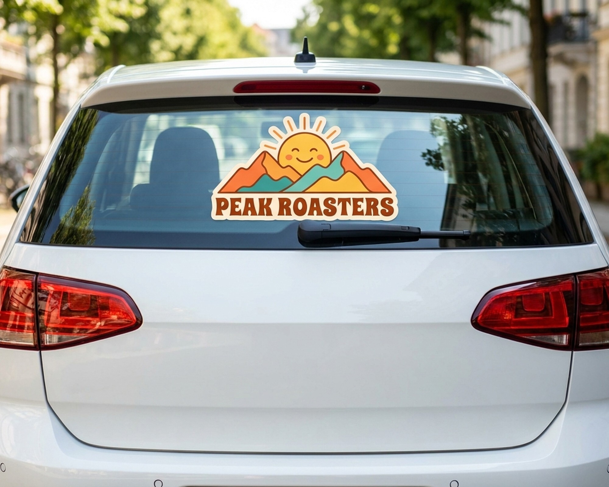 Muotoon leikattu oma dekaali, jossa aurinko- ja vuorilogo sekä teksti "Peak Roasters", auton takalasissa