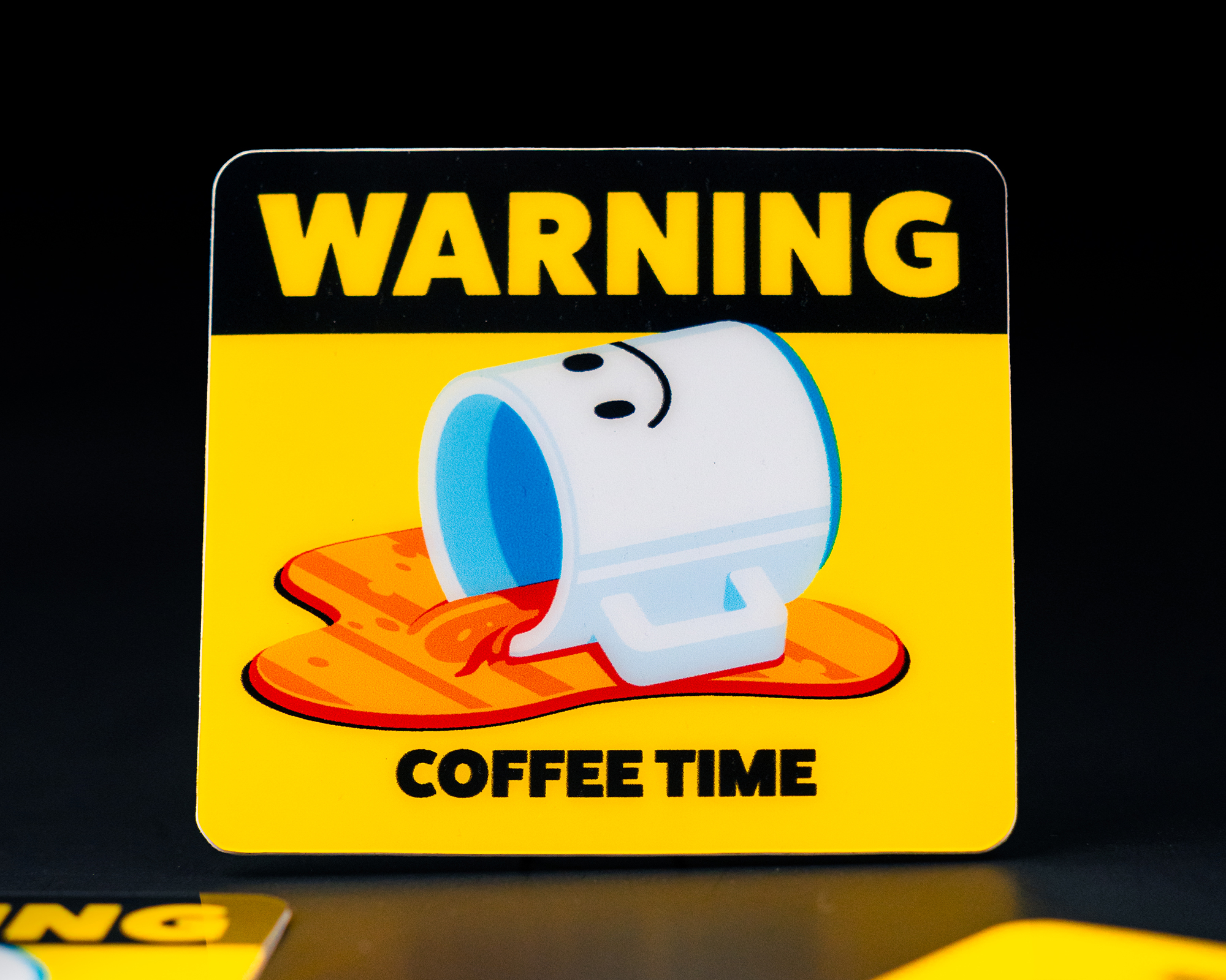Yellow and black sticker with a cartoon mug spilling coffee and the text "WARNING COFFEE TIME."