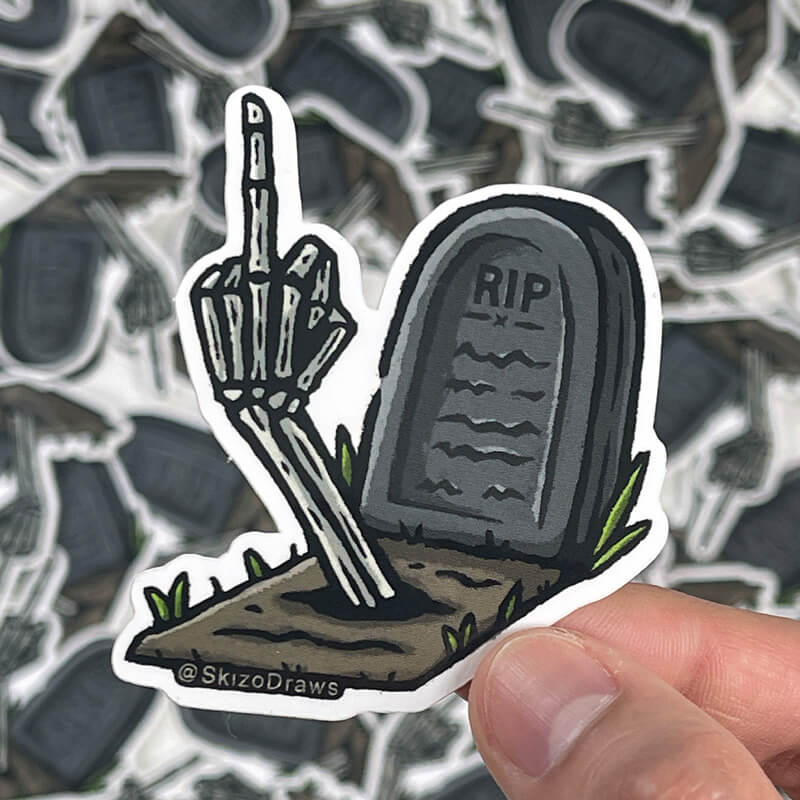 Muotoon leikattu vinyylitarra, jossa on hautakivi tekstillä "RIP" ja maasta nouseva luurangon käsi näyttämässä keskisormea. Taustalla tarroja.